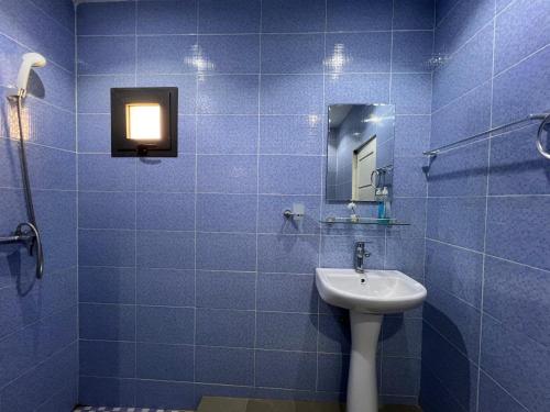 a blue tiled bathroom with a sink and a mirror at Studio Villa Hortensia in Dakar