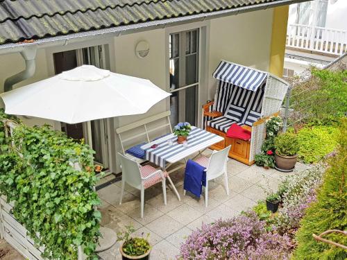 une terrasse avec une table, des chaises et un parasol dans l'établissement Villa Rosa - Apt. 15, à Sellin