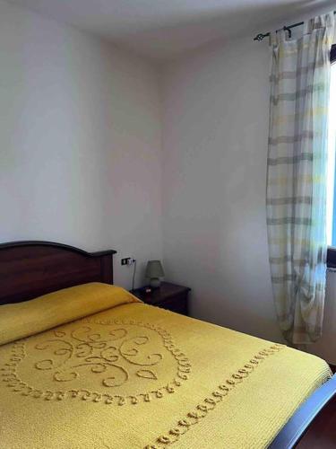 a bedroom with a bed with a yellow blanket on it at Casa nuova indipendente in Sardegna in Laerru