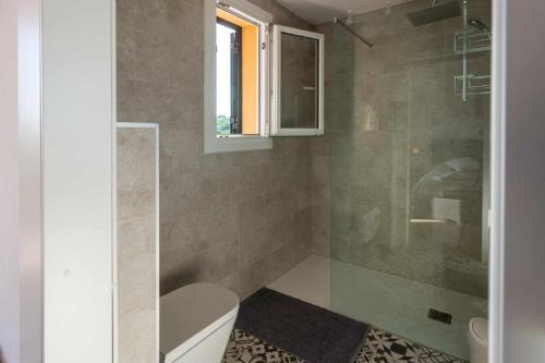 a bathroom with a toilet and a glass shower at Casa Alegría Casa premium piscina comunitaria in S'agaro