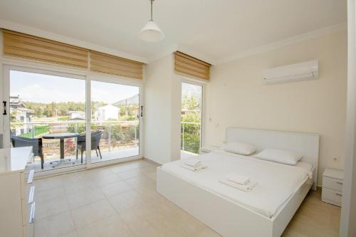 a white bedroom with a bed and a balcony at Villa Valley 5 in Oludeniz