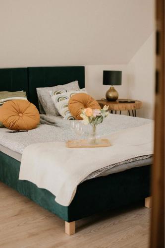 a green bed with a vase of flowers on it at Green House Relax in Płaska