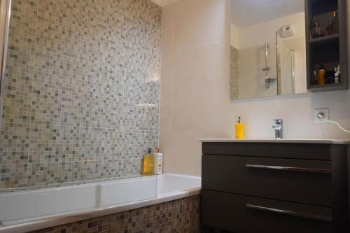 une salle de bain avec une baignoire et un lavabo dans l'établissement Appartement Olympic games 2024, à Clichy