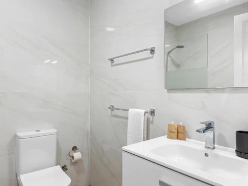 Baño blanco con aseo y lavamanos en Elegant apartment with private workspace, en Candelaria