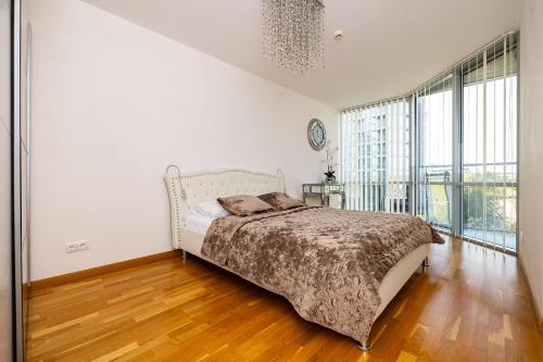 a white bedroom with a bed and a large window at Elija Swan-Toy Apartments in Šventoji
