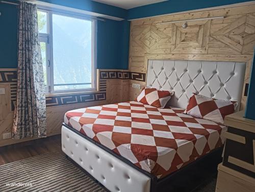 a bedroom with a large bed with a checkered blanket at Wanderers Homestay -All mountain facing rooms in Kalpa