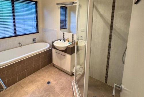 La salle de bains est pourvue d'une baignoire, d'un lavabo et d'une douche. dans l'établissement Our Beach House K'gari, à Fraser Island