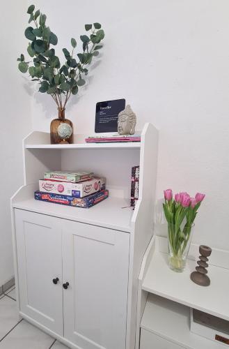 a white book shelf with books and flowers in a vase at Ferienwohnung Rote Tür - Landleben pur! in Kirchhain