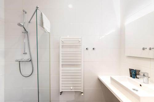 a white bathroom with a shower and a sink at YAYS Amsterdam Salthouse Canal by Numa in Amsterdam