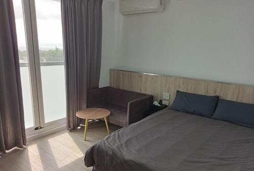 sypialnia z łóżkiem, krzesłem i oknem w obiekcie 大鯨魚旅宿 w mieście Lü Dao
