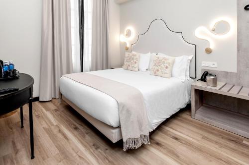 a bedroom with a white bed and a desk at Hotel Casa Palacete Tablas by Maxi Hoteles in Granada