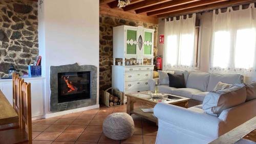 Casa Rural Lucia في La Horcajada: غرفة معيشة مع أريكة ومدفأة