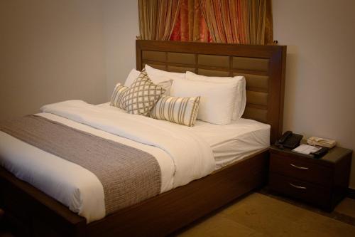 Una cama con sábanas blancas y almohadas. en Xefan Hotels, en Karachi