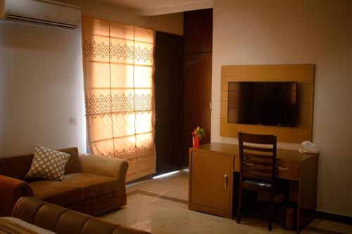a living room with a couch and a chair and a television at Xefan Hotels in Karachi