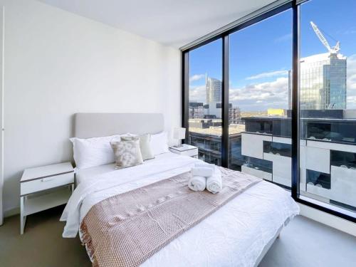 a bedroom with a white bed and a large window at Pride Manor South Yarra in Melbourne