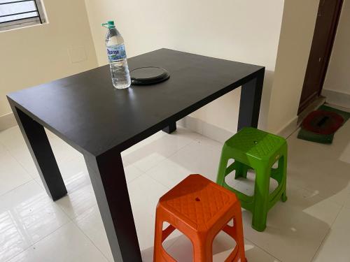 ein schwarzer Tisch mit einer Flasche Wasser und zwei Hockern in der Unterkunft The Lakeview Apart-Hotel in Agartala