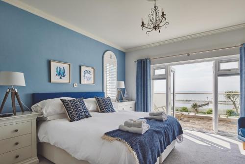 a bedroom with blue walls and a bed with a window at Sun Beach House in Middleton-on-Sea