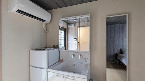a kitchen with a white refrigerator and a mirror at 与那国むんぶステイ祖納 in Sonai