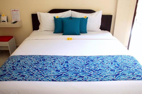 uma cama com lençóis e almofadas azuis e brancos em Djembank Hotel em Tjakranegara