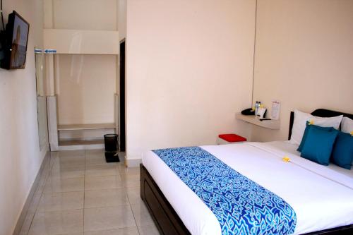 Djembank Hotel في Tjakranegara: غرفة نوم بسرير كبير وملاءات زرقاء وبيضاء