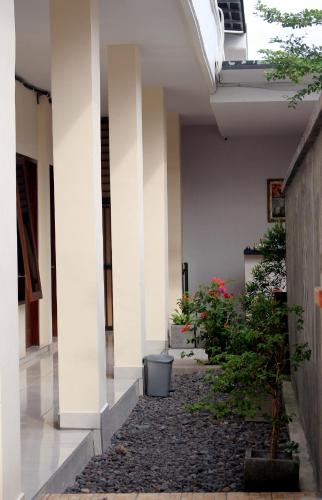 Djembank Hotel في Tjakranegara: مدخل مبنى فيه اعمدة بيضاء ونباتات