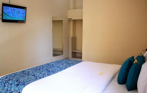 um quarto com uma cama e uma televisão na parede em Djembank Hotel em Tjakranegara