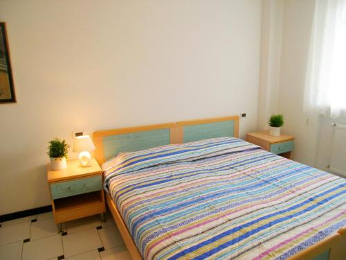 1 dormitorio con 1 cama con 2 mesitas de noche y 2 plantas en Condominio Frontemare, en Grado