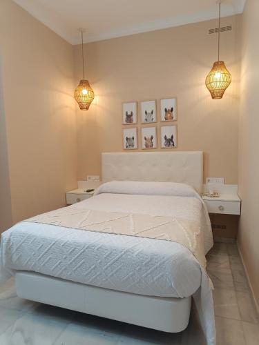 a bedroom with a white bed and two lights at Casa Palacio Don Pedro in Seville