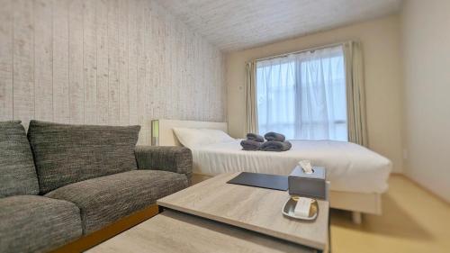 ein Wohnzimmer mit einem Sofa und einem Bett in der Unterkunft 与那国むんぶステイ空港前 in Sonai