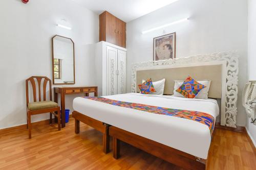 um quarto com uma cama grande e uma cadeira em FabHotel Prime Fair stayz em Goa