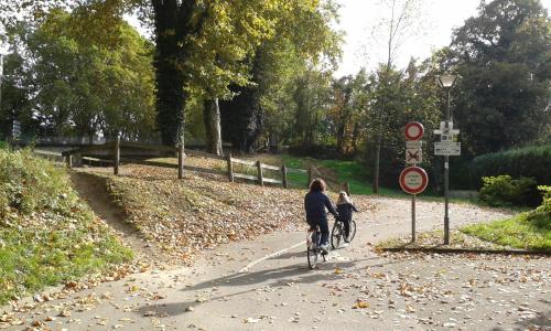 two people riding bikes down a path in a park at Gîte Des Vergers in Illkirch-Graffenstaden