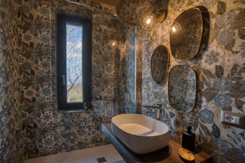 a bathroom with a sink and mirrors on the wall at PaterMater b&b - La stanza di Rol in CastellʼAzzara