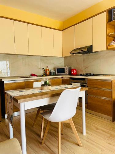 una cucina con tavolo di legno e sedie bianche di Boat Apartment a Durrës