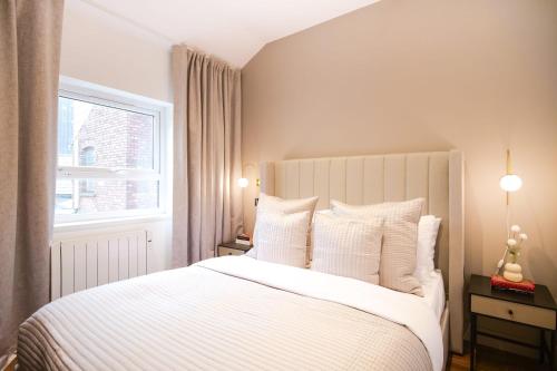 1 dormitorio con 1 cama con sábanas blancas y ventana en Smithfield by The Heim Residences, en Mánchester