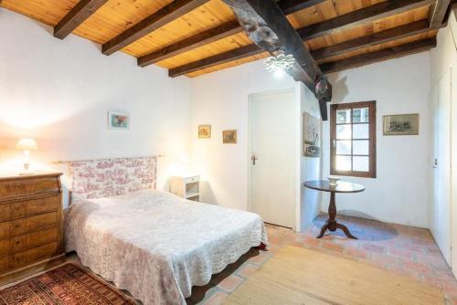 a bedroom with a bed and a table in a room at Maison landaise avec jardin clos, idéal pour animaux in Lacquy
