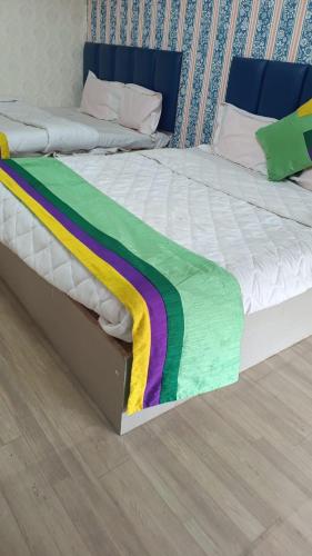 uma cama com um cobertor de arco-íris em cima em Hotel Sawariya em Ahmedabad
