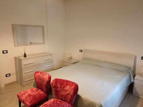 1 dormitorio con 1 cama y 2 sillas rojas en Tirrenia Appartamento Girasoli en Tirrenia
