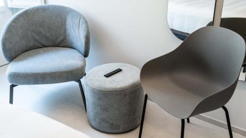 a chair and a stool with a remote control on it at Amatera Luxury Apartments in Matera