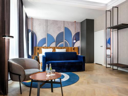 Mercure Krakow Fabryczna City في كراكوف: غرفة في الفندق مع أريكة زرقاء وطاولة