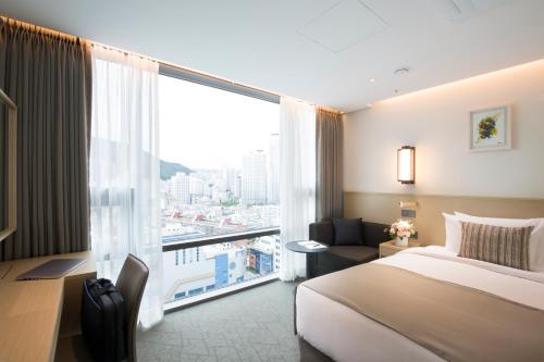 a hotel room with a bed and a large window at Hotel Centralbay in Busan