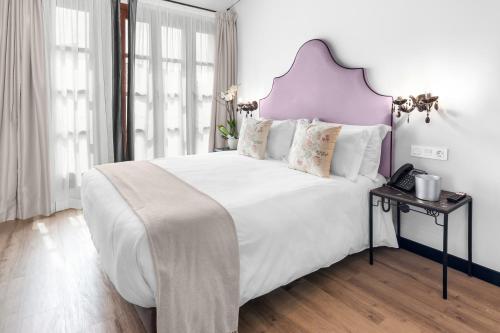a bedroom with a large white bed with a purple headboard at Hotel Casa Palacete Tablas by Maxi Hoteles in Granada