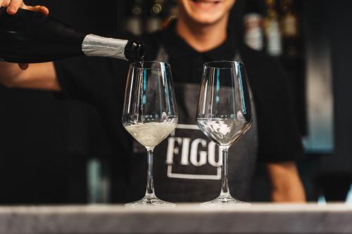 a man pouring white wine into two wine glasses at Noba Hotel e Residenze in Rome
