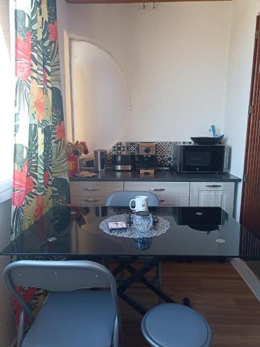 une table dans une pièce avec un comptoir avec un micro-ondes dans l'établissement Port Leucate Appartement 6 Voyageurs - 150 m de la plage, à Leucate