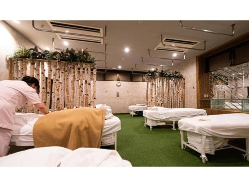 a man is making beds in a hospital room at Male Only Capsule Hotel & Sauna G-topia - Vacation STAY 70068v in Funabashi