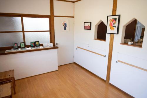 um quarto com portas e janelas brancas e piso de madeira em ikibase Guest House em Iki