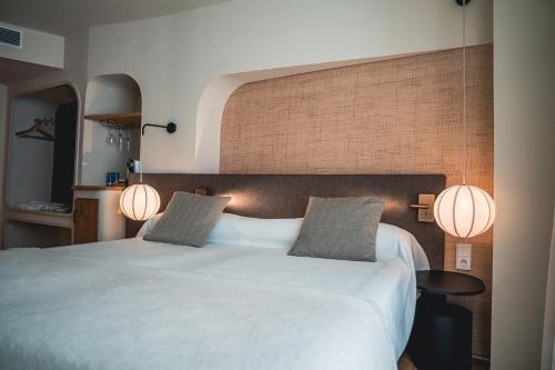 a bedroom with a large white bed with two lamps at Pacha Hotel in Ibiza Town