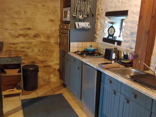 uma cozinha com um lavatório e um fogão forno superior em Charming typical Auvergne cottage em Teilhet