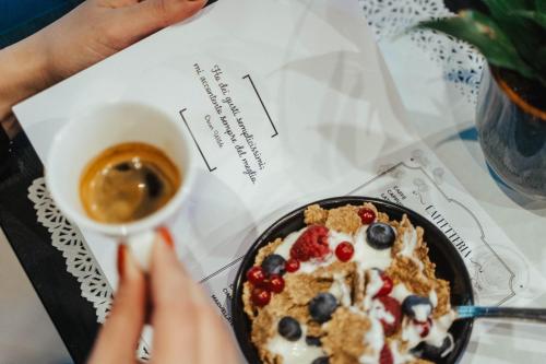 a person sitting at a table with a plate of food and a cup of coffee at Noba Hotel e Residenze in Rome