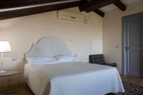 a bedroom with a white bed and a chair at Masseria Celentano Relais & Agriturismo in San Severo