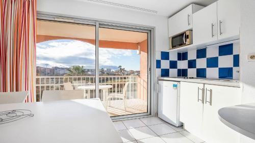 - une cuisine avec vue sur un balcon dans l'établissement PRIMAVERA 202 Appt veranda 4 a 6 pers, au Cap d'Agde